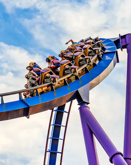 Roller coaster at Six Flags Discovery Kingdom with riders on a loop against a blue sky.