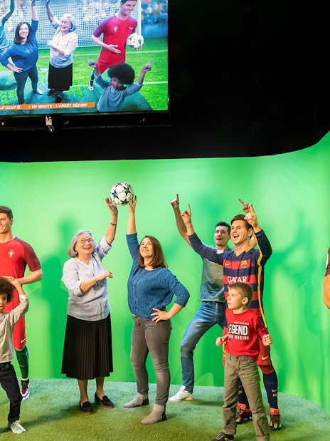 Statues of Lionel Messi and Kylian Mbappe at Grévin Paris wax museum with visitors.
