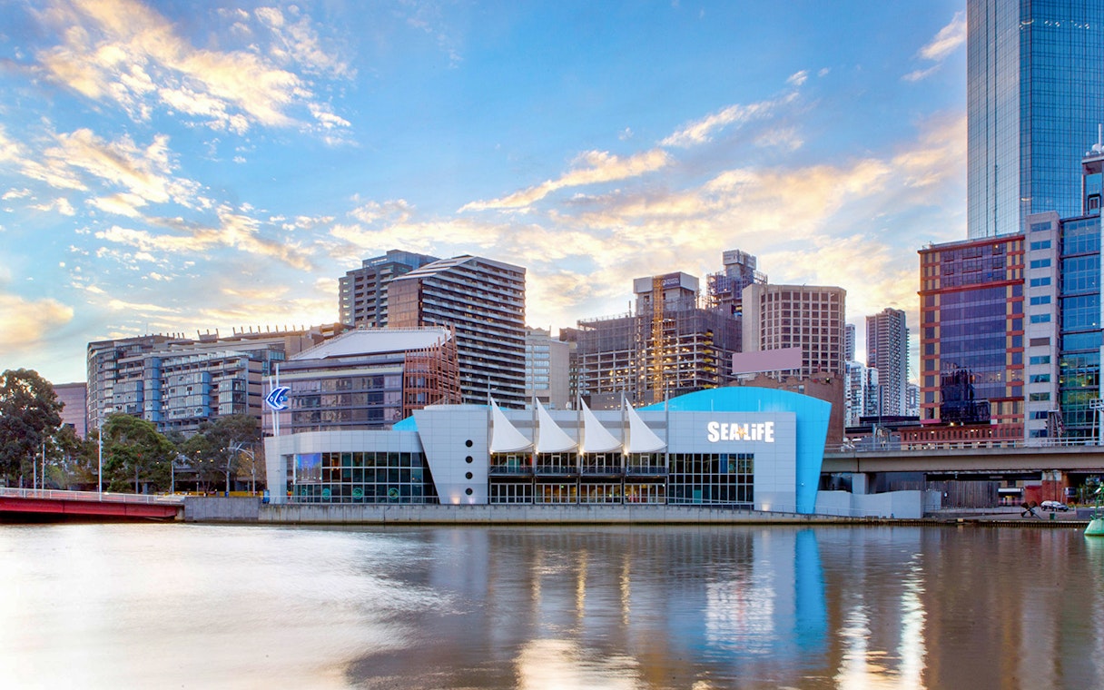 SEA LIFE Melbourne Aquarium exterior by the river with city skyline.