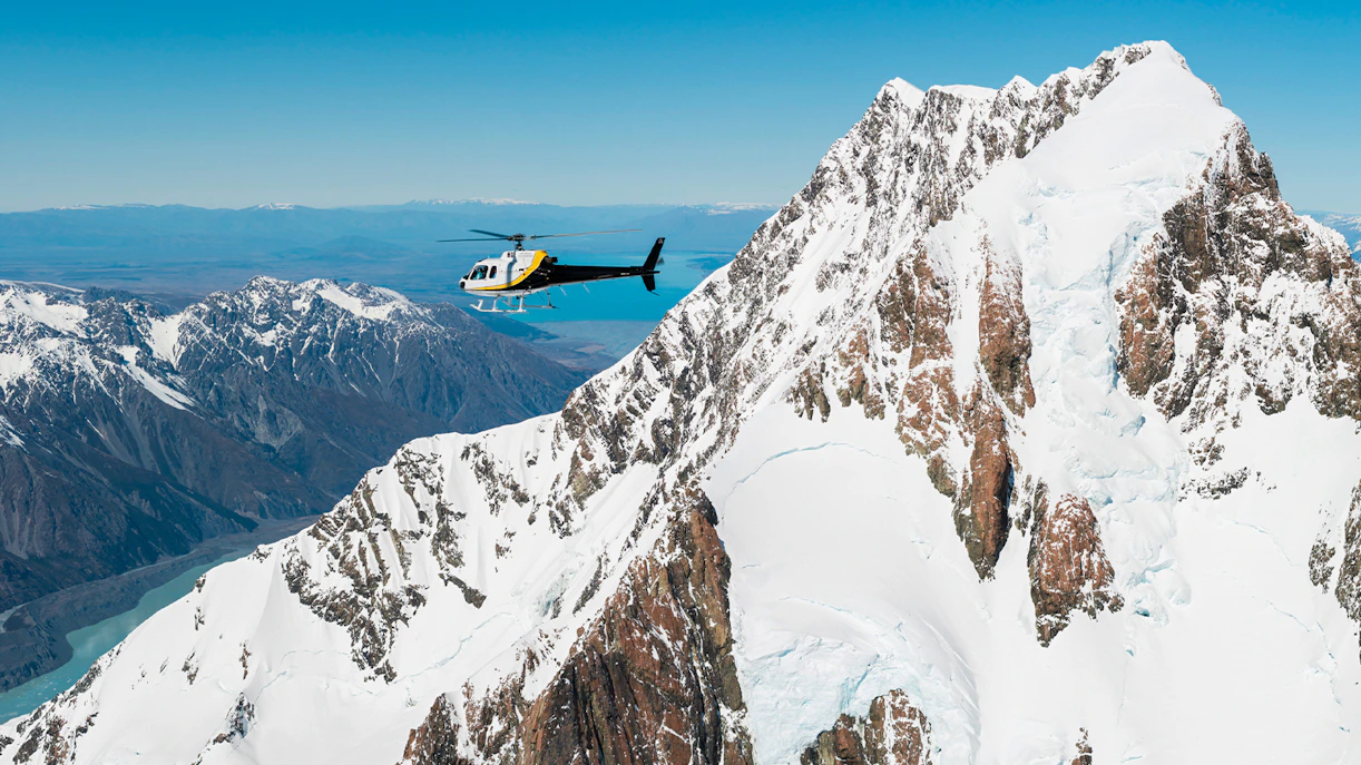 Helicopter flying over snow-covered peaks near Fox Glacier, New Zealand.