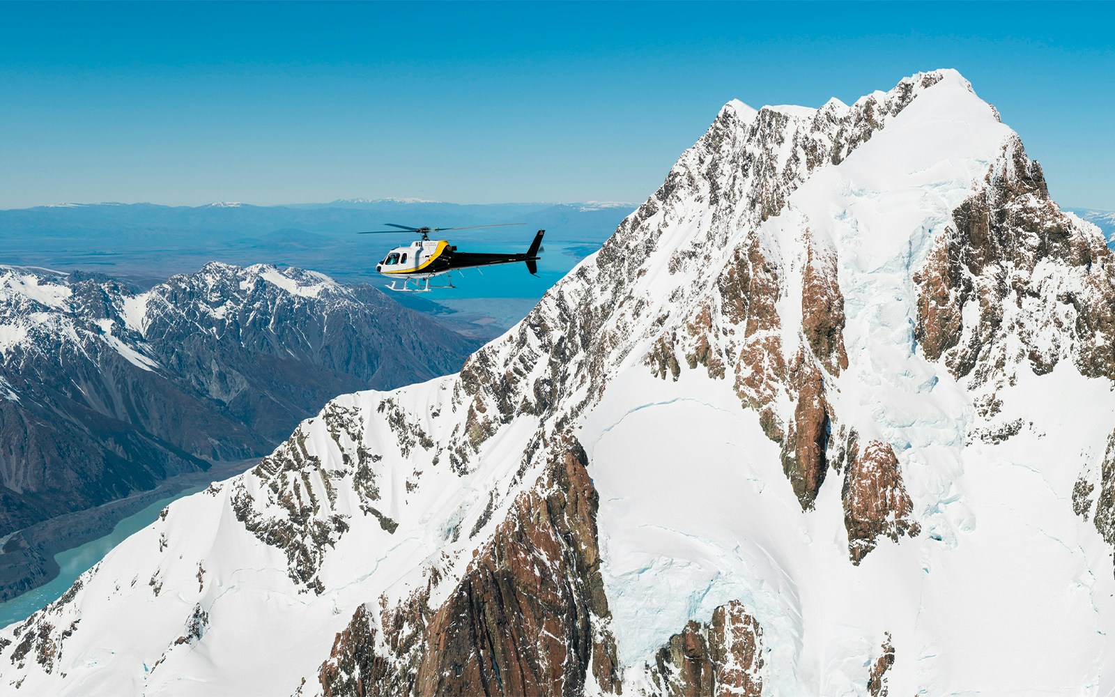 Helicopter flying over snow-covered peaks near Fox Glacier, New Zealand.