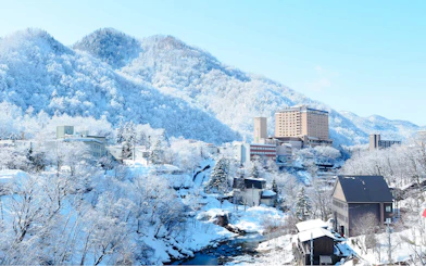 Snow-covered landscape with buildings and mountains in Sapporo, Hokkaido.
