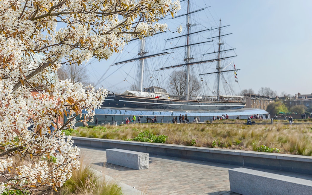 Cutty Sark ship with blooming tree in Greenwich garden, London.