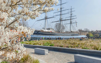 Cutty Sark ship with blooming tree in Greenwich garden, London.