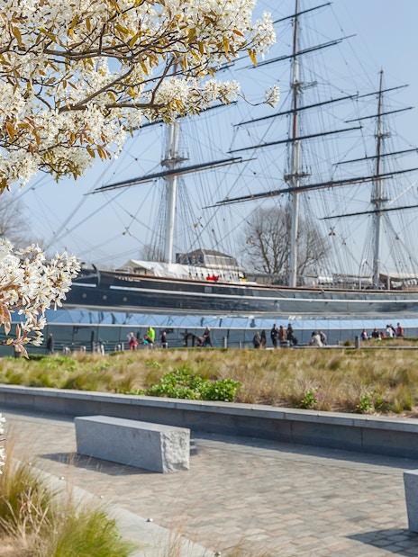 Cutty Sark ship with blooming tree in Greenwich garden, London.