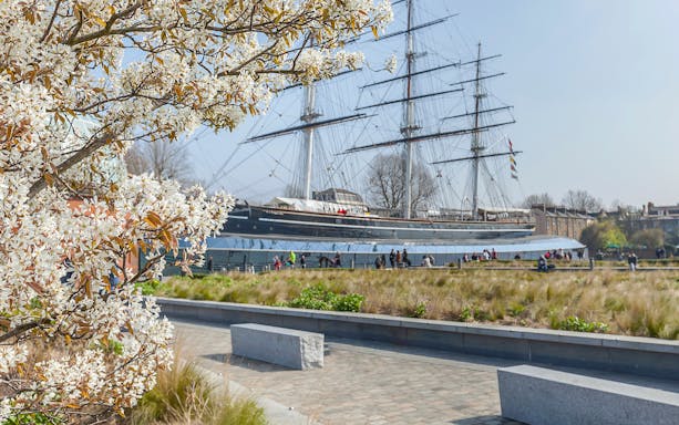 Cutty Sark ship with blooming tree in Greenwich garden, London.