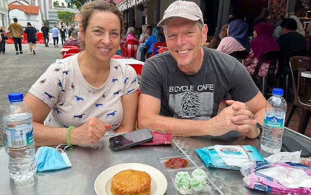 Couple enjoying local snacks at an outdoor cafe during the Bike and Bites Food Tour.