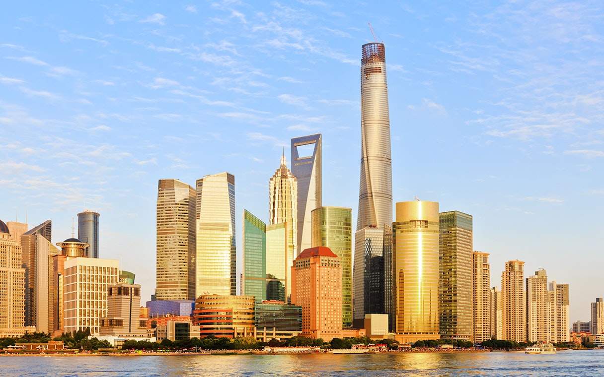 Shanghai skyline with modern skyscrapers at dusk, including the Shanghai Tower and World Financial Center.