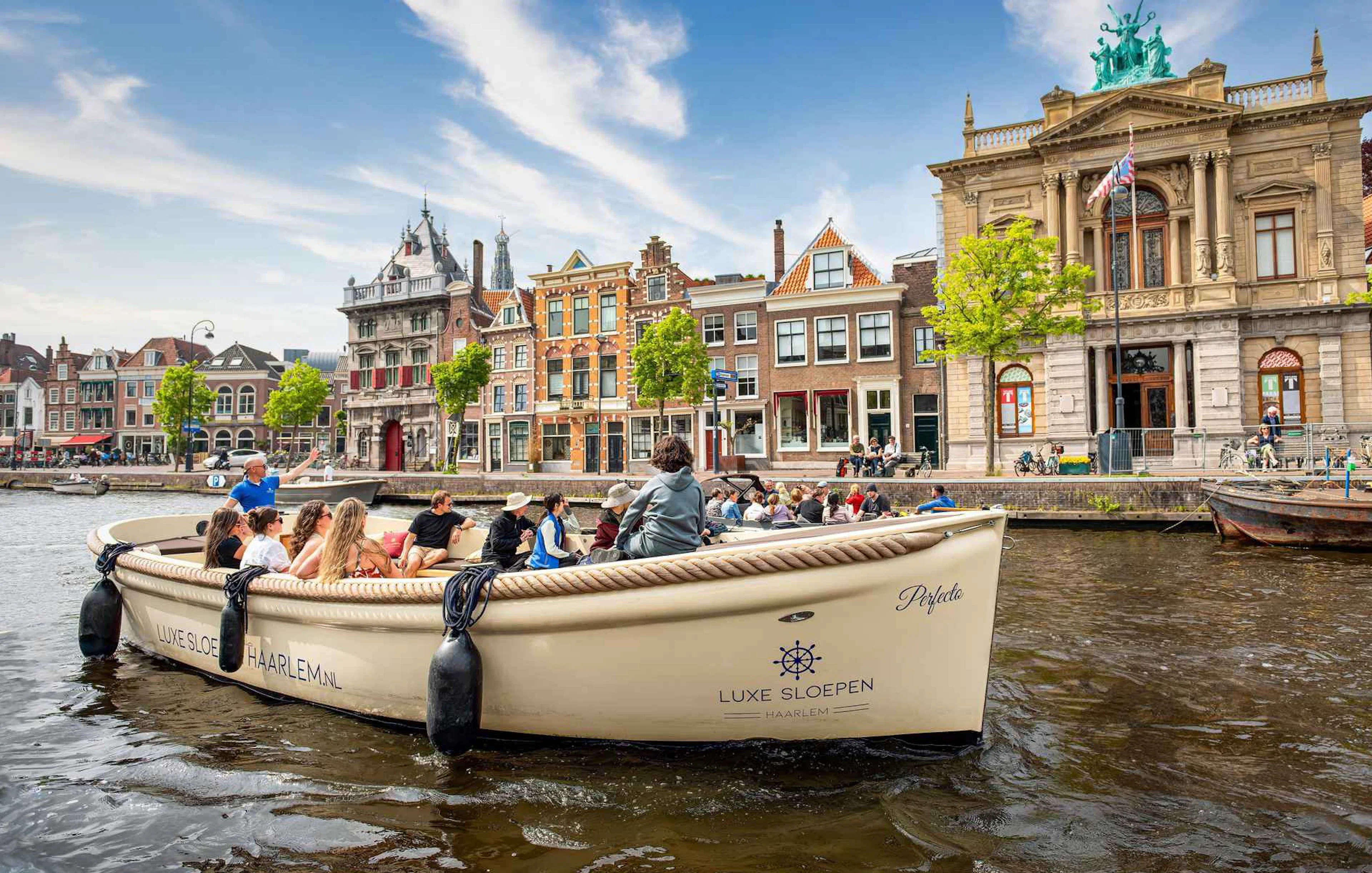 Open boat cruising through Haarlem canal with historic buildings in the background.