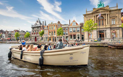 Open boat cruising through Haarlem canal with historic buildings in the background.