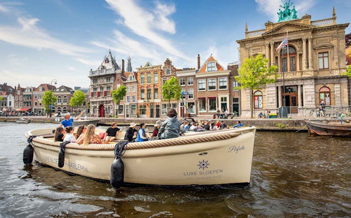Open boat cruising through Haarlem canal with historic buildings in the background.
