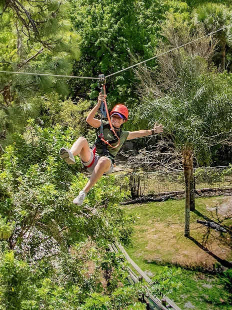 Tourist zip lining over alligator habitat at Gatorland, Florida.