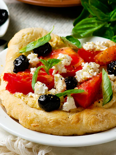 Santorini catamaran cruise meal with Greek salad on flatbread, featuring tomatoes, olives, and feta.