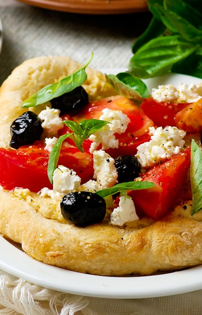 Santorini catamaran cruise meal with Greek salad on flatbread, featuring tomatoes, olives, and feta.