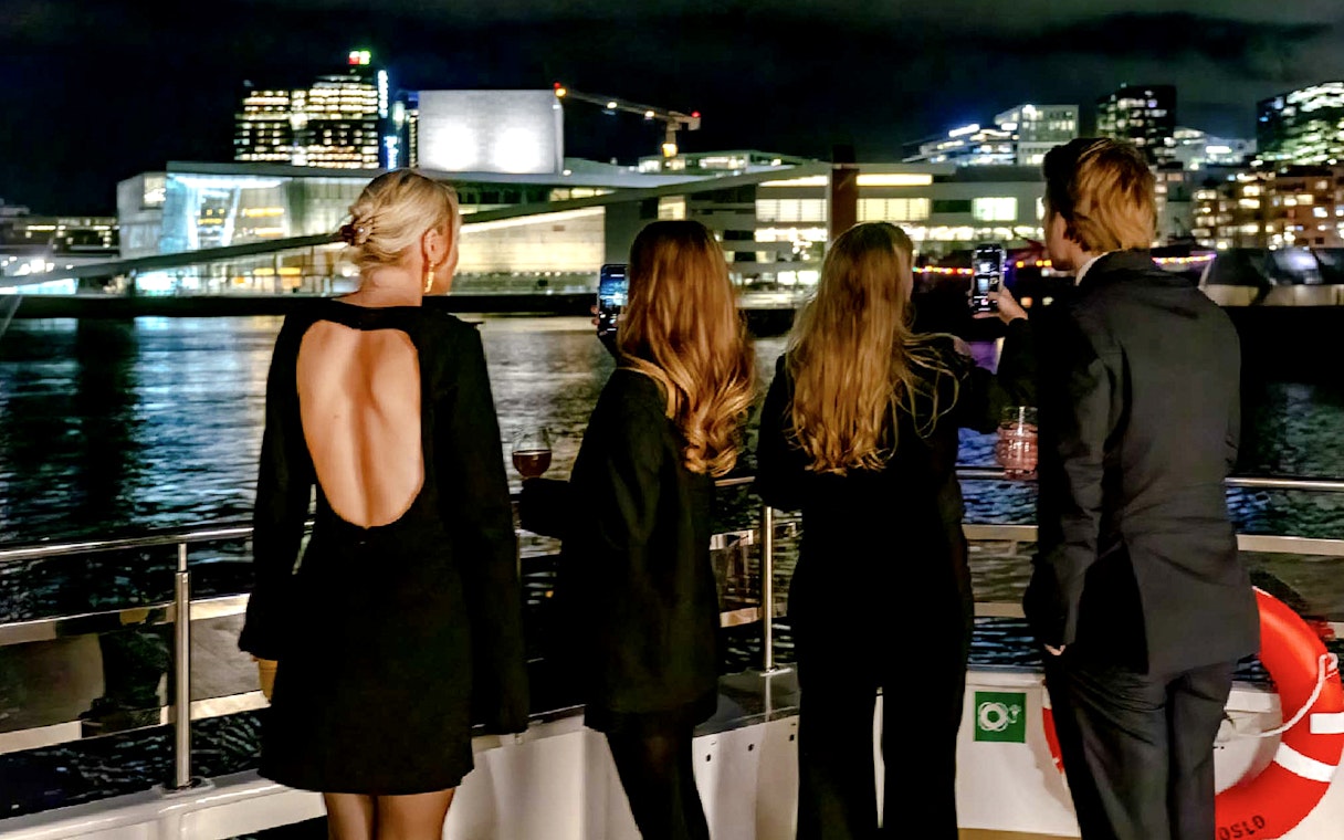 Guests enjoying Oslo skyline on a dinner cruise at night.
