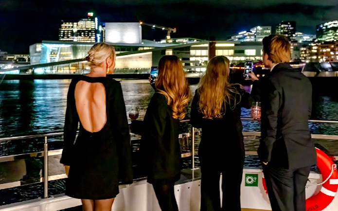 Guests enjoying Oslo skyline on a dinner cruise at night.