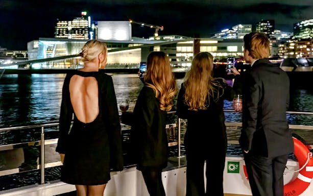 Guests enjoying Oslo skyline on a dinner cruise at night.