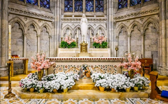 Altar adorned with flowers inside St Patrick Cathedral, featuring intricate stone carvings and stained glass.