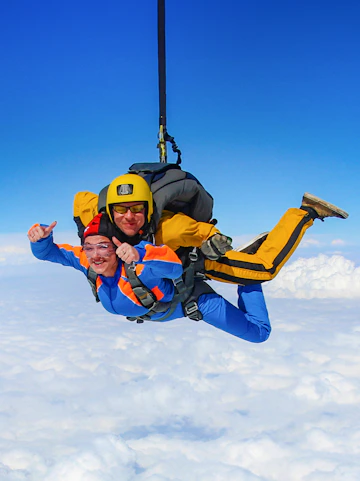 Tandem skydivers freefalling above clouds on Sunshine Coast.