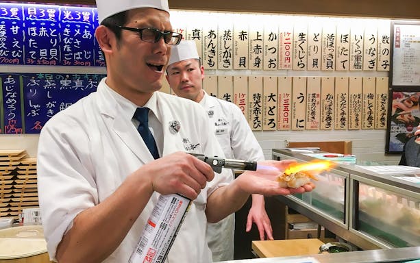 Sushi chef torching nigiri at a Shibuya restaurant during a food tour.