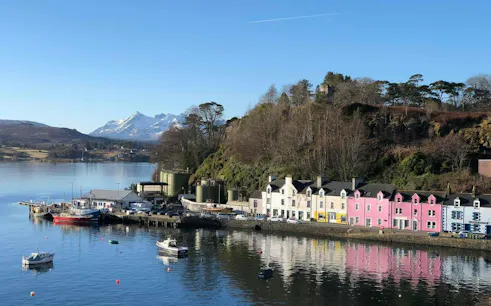 Colorful houses along Portree harbor with mountains in the background, Isle of Skye, Scotland.