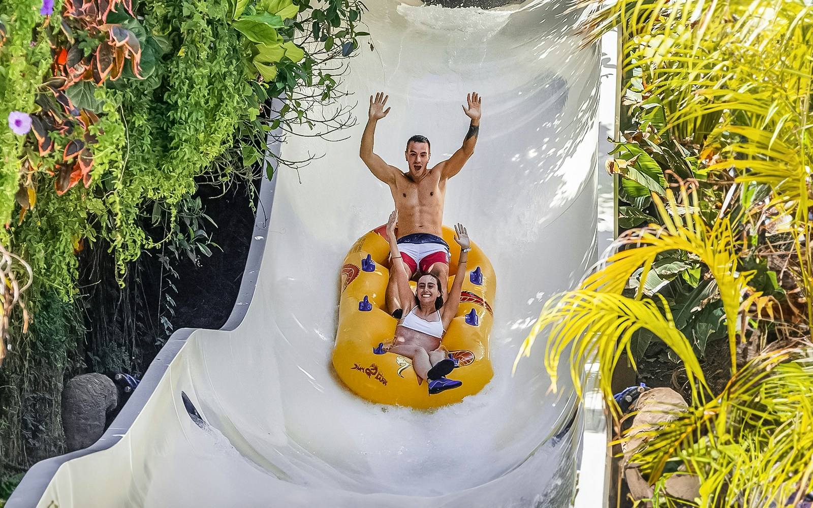 Group of excited tourists enjoying a thrilling water slide ride with Skip-the-Line Tickets at Siam Park, Tenerife