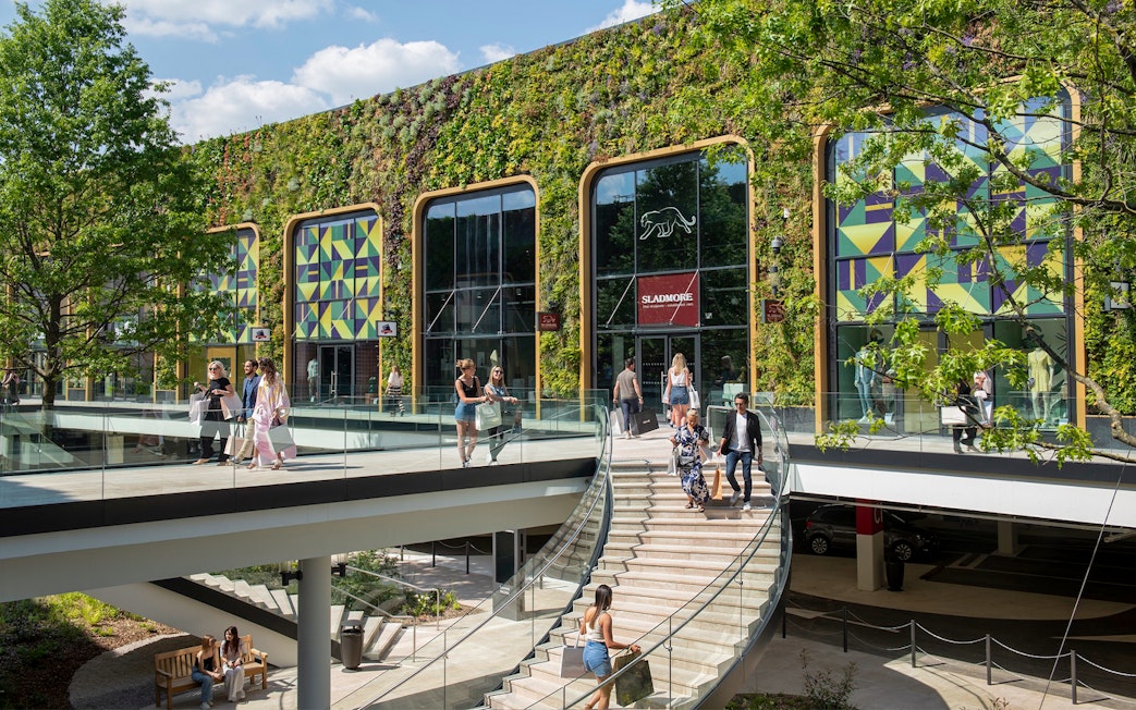 Visitors walking through a modern shopping area with a green facade in Paris.