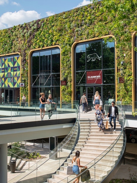 Visitors walking through a modern shopping area with a green facade in Paris.