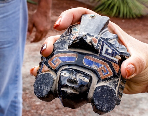 Tourist guide presenting obsidian handcraft to visitors at Teotihuacan archaeological site.