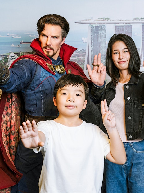 Wax figure of a superhero with visitors at Madame Tussauds Singapore, Marina Bay Sands backdrop.