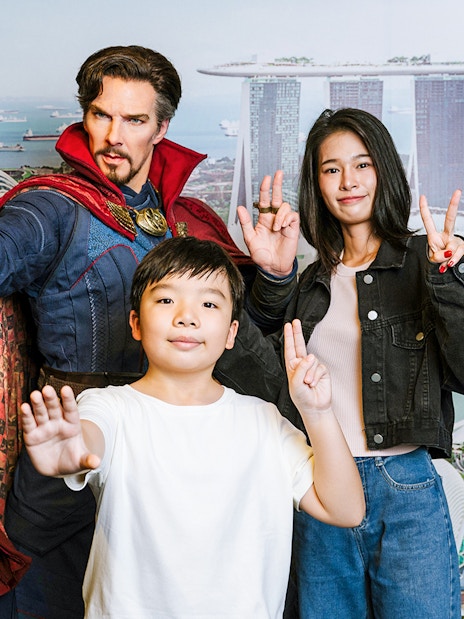 Wax figure of a superhero with visitors at Madame Tussauds Singapore, Marina Bay Sands backdrop.