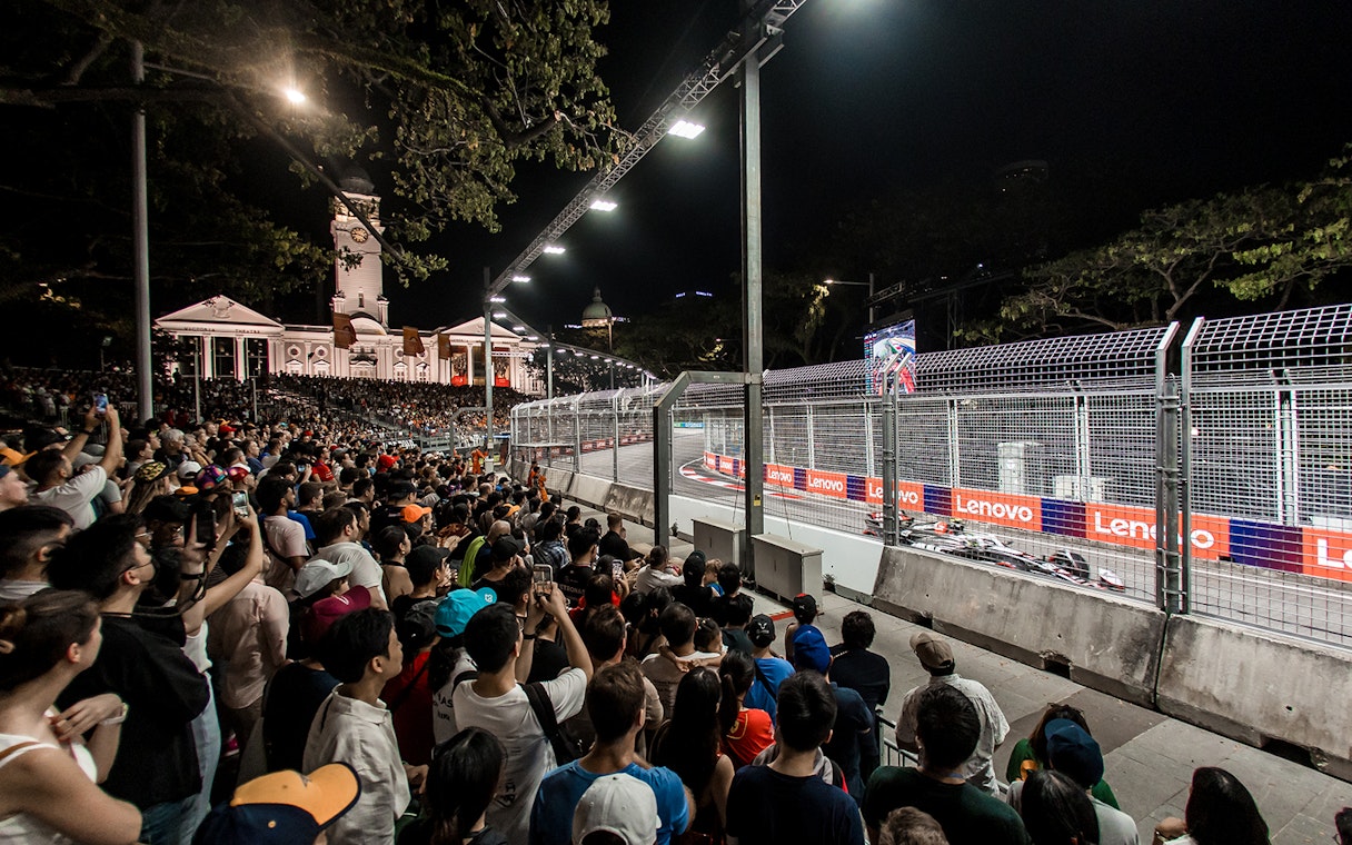 Spectators watching F1 race at Zone 4 Walkabout, Singapore, with cars on track.