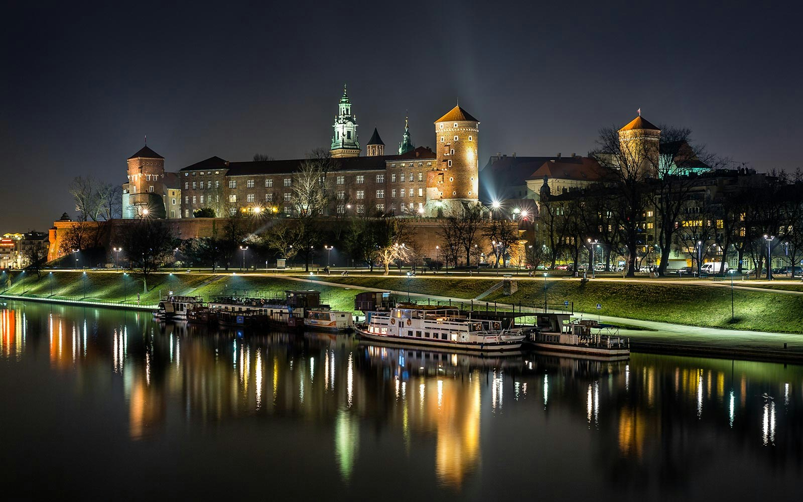 Vistula River night cruise with illuminated Krakow skyline in the background.
