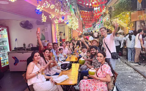 Group enjoying street food at a vibrant night market in Hanoi during a Jeep culture tour.