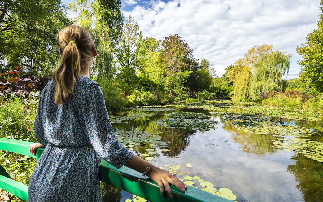 Visitor admiring water lilies at Monet's Gardens in Giverny during a half-day tour from Paris.