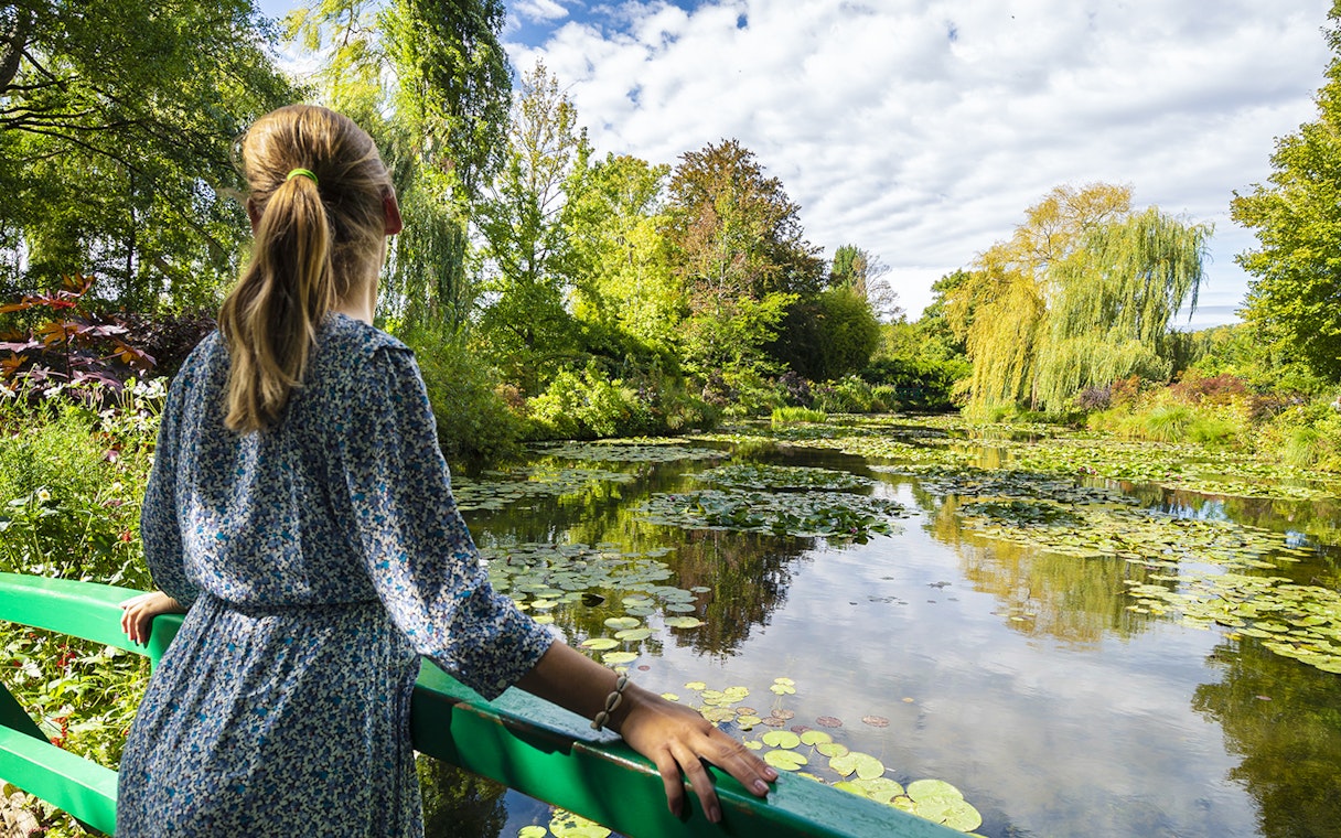 Visitor admiring water lilies at Monet's Gardens in Giverny during a half-day tour from Paris.