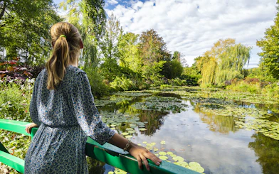 Visitor admiring water lilies at Monet's Gardens in Giverny during a half-day tour from Paris.
