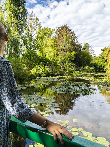 Visitor admiring water lilies at Monet's Gardens in Giverny during a half-day tour from Paris.
