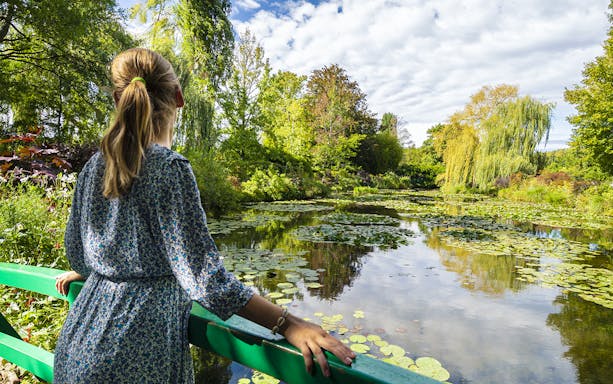 Visitor admiring water lilies at Monet's Gardens in Giverny during a half-day tour from Paris.