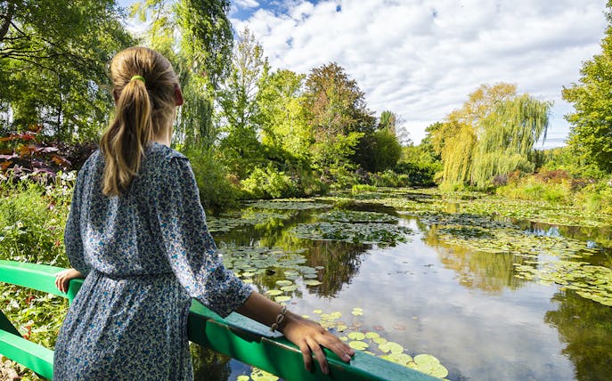 Visitor admiring water lilies at Monet's Gardens in Giverny during a half-day tour from Paris.