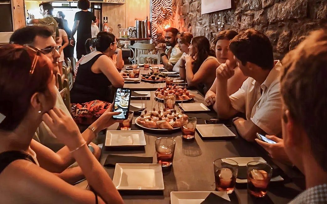 Group enjoying tapas at a long table during a food tour in Barcelona.