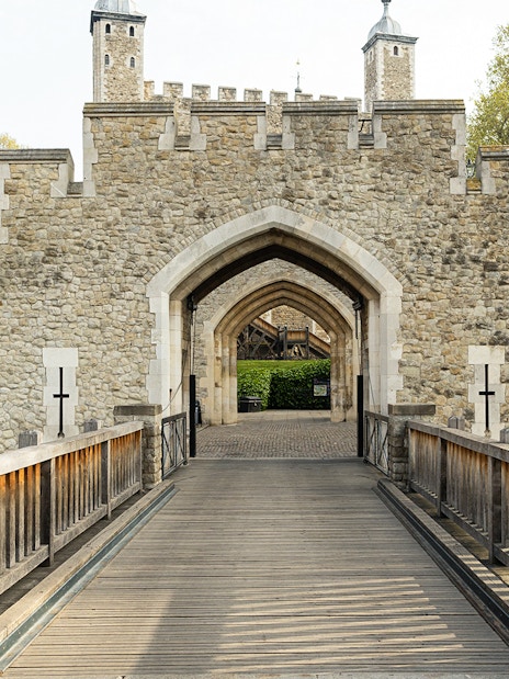 Tower of London entrance gate with stone walls and wooden bridge.