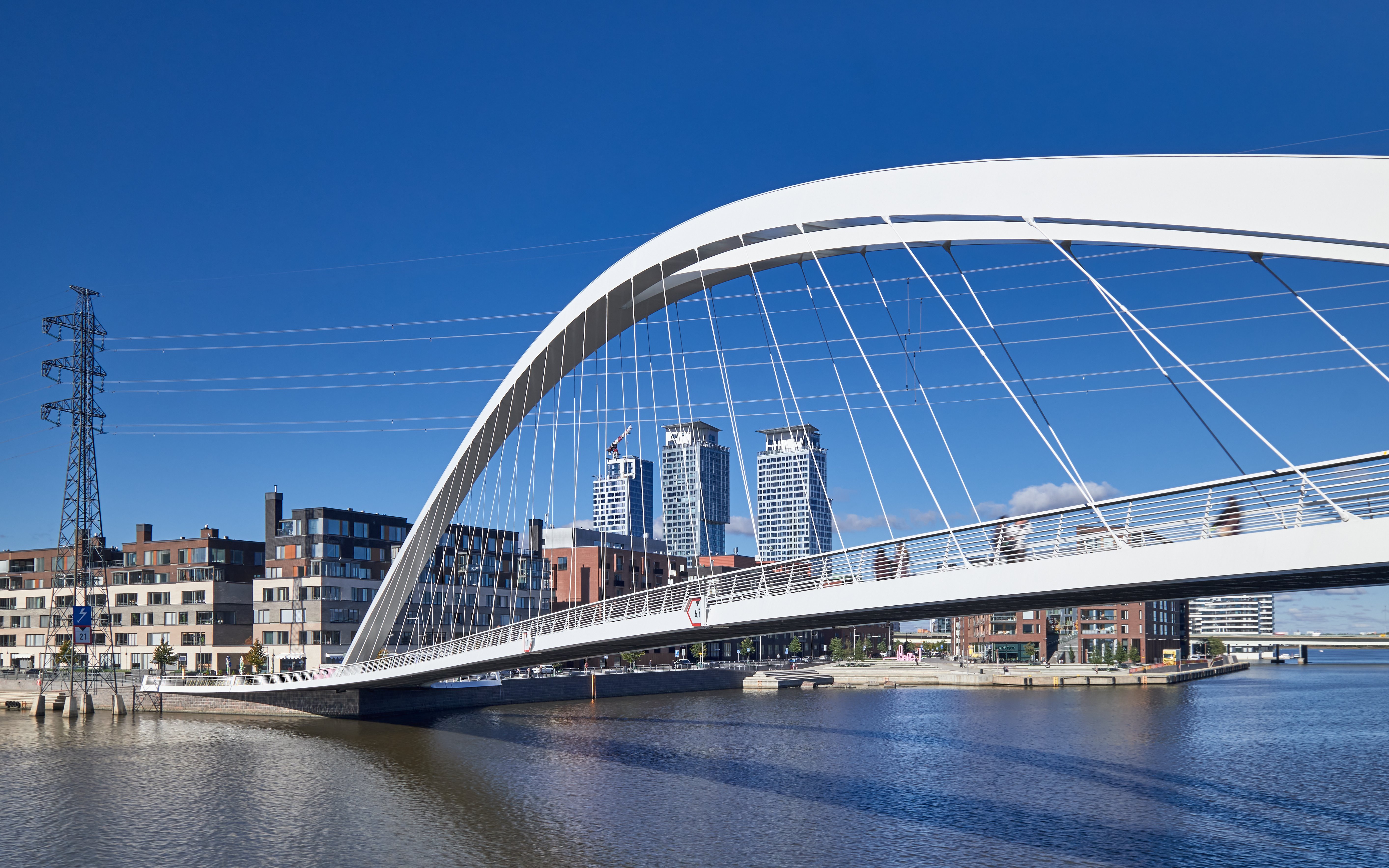 Modern bridge spanning water in Kalasatama district, Helsinki, with cityscape in background.