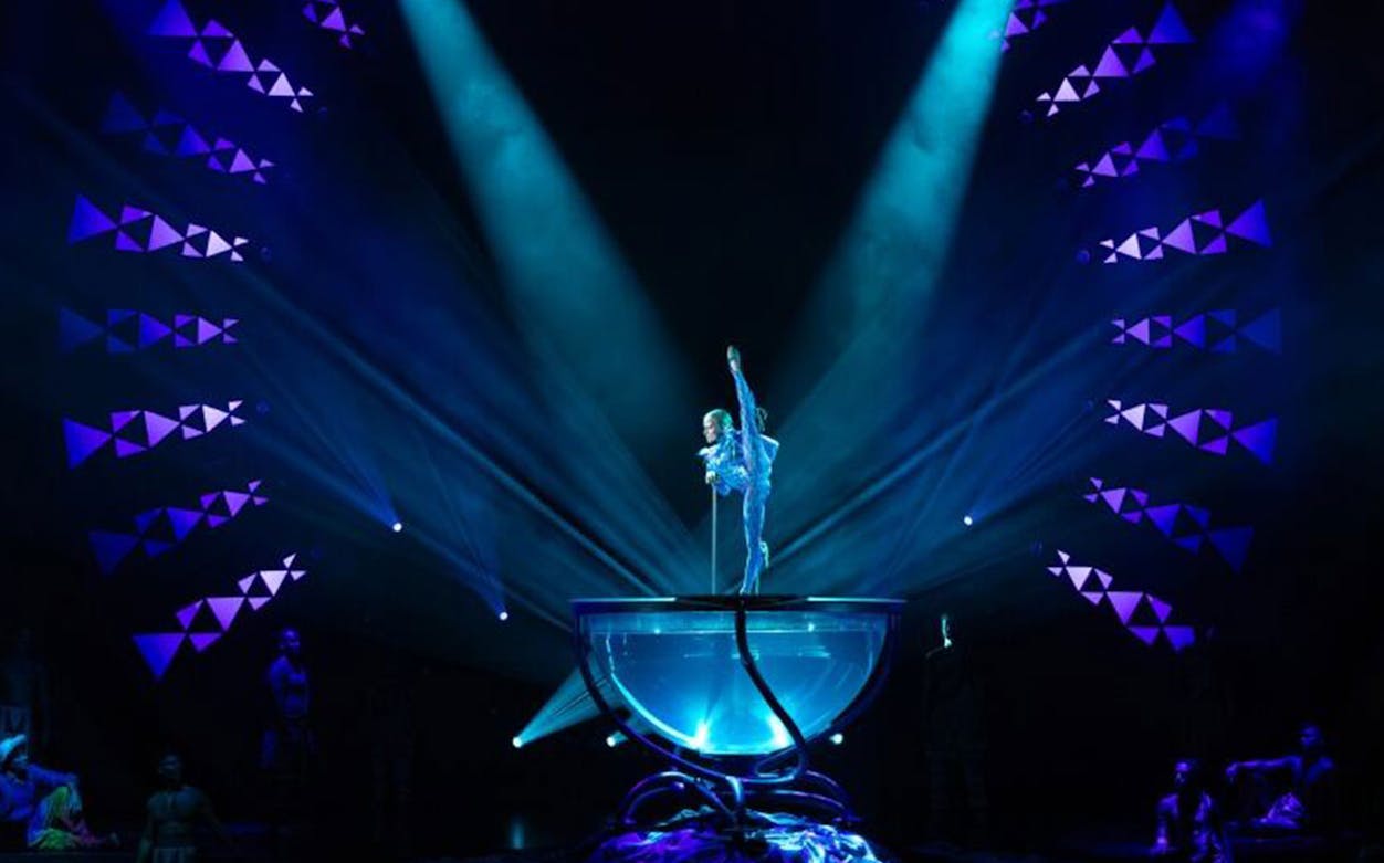 Performer balancing on a pole in a vibrant stage show, Auana.