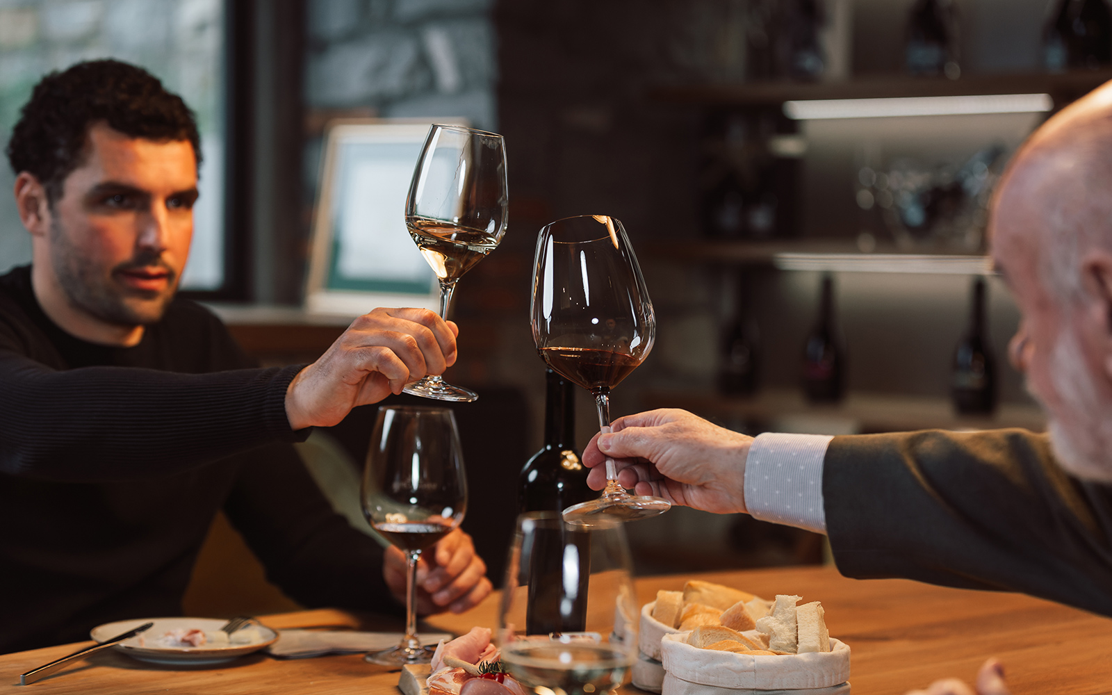 Wine tasting group toasting with glasses in a cozy cellar setting.