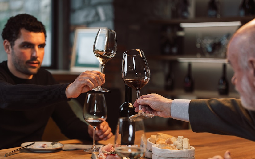 Wine tasting group toasting with glasses in a cozy cellar setting.
