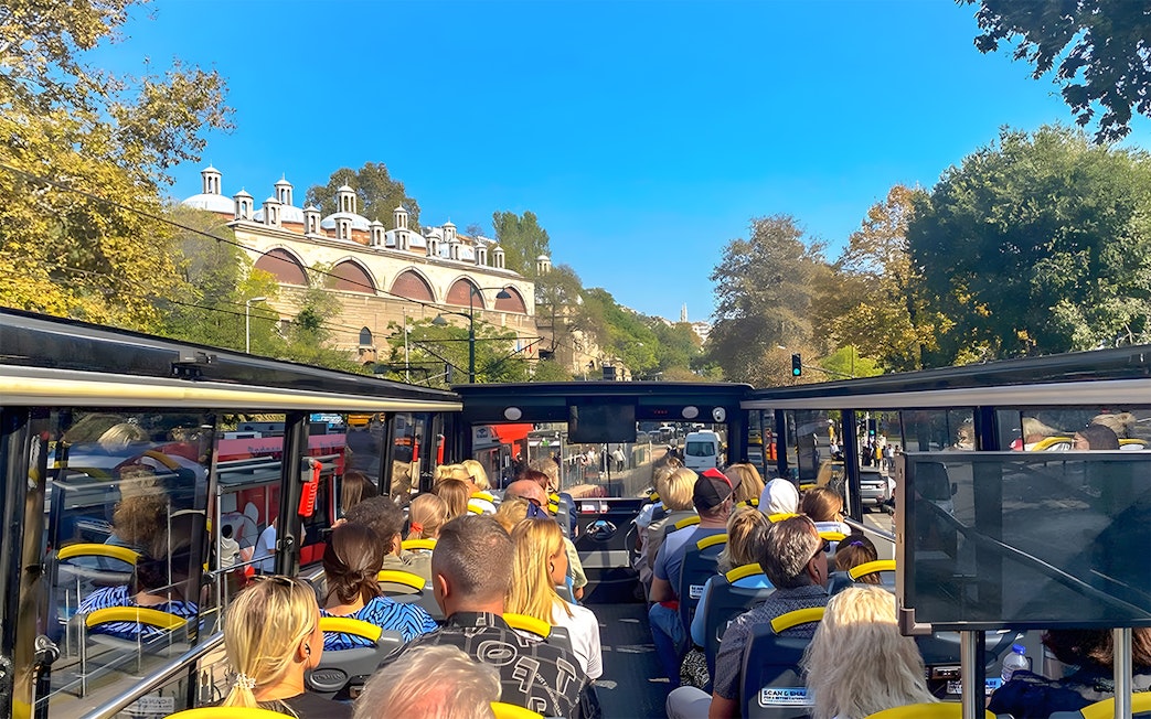 Open-top bus tour in Istanbul passing by historic architecture.