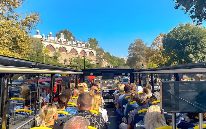 Open-top bus tour in Istanbul passing by historic architecture.