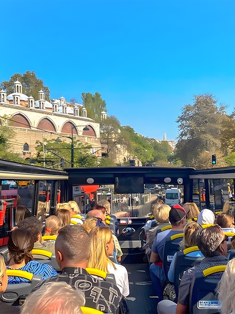 Open-top bus tour in Istanbul passing by historic architecture.