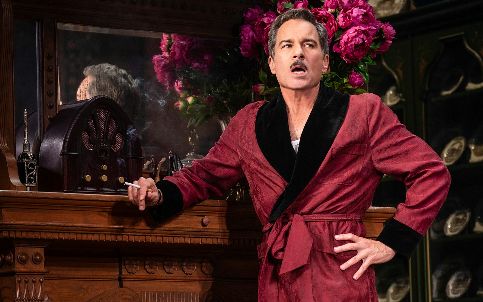 Man in a red robe with a vintage radio and flowers at The Cottage.